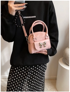 Detailed close-up of pink quilted bucket bag with gold bow clasp and beaded pendant