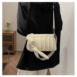 Vista dettagliata della borsa a pieghe beige con grande fiocco su giacca nera