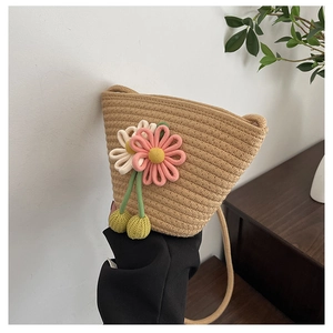Detail of woven straw bucket bag featuring 3D fabric flowers and cherry pendant charms