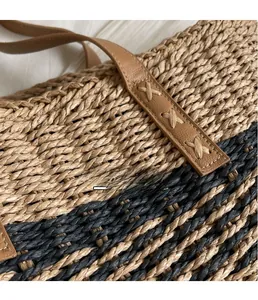 Close-up of woven straw texture with brown leather strap and reinforced X-stitching