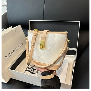Detail view of mini bucket bag with ice-crack texture and golden rotary lock in a gift box