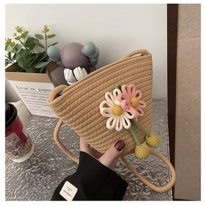 Detail of woven straw bucket bag featuring handmade daisy flowers and tassel charms