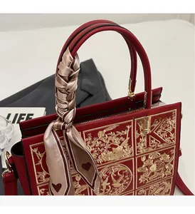 Detail of red leather wedding handbag with gold floral embroidery and decorative silk scarf