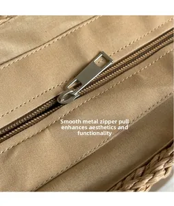 Detailed close-up of smooth silver metal zipper pull on a straw and canvas beach bag