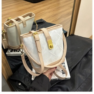 Detail of white and beige bucket bag with geometric embossed texture and gold twist lock