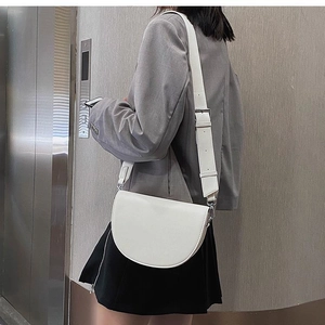 Detail of white semi-circle saddle bag with wide adjustable strap on a female model