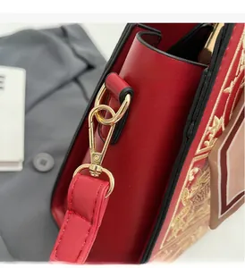 Close-up of red leather wedding bag featuring golden embroidery and metallic lobster clasp