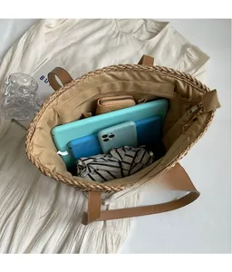 Top view of large straw tote bag showing spacious interior with leather straps and gadgets