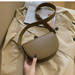 Detail of smooth olive leather saddle bag on trench coat with wide shoulder strap