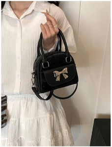Detail showing black velvet shell-shaped handbag with a silver metal bow accent