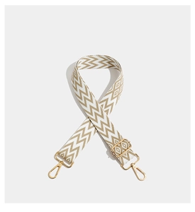 Detail of bohemian geometric embroidered wide strap with golden metal carabiner hooks