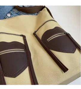 Detail of beige canvas tote featuring brown heart-shaped leather pockets and zipper
