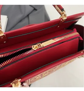 Detail of high-quality golden metal zipper on a premium red leather wedding handbag