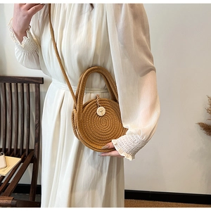 Detailed texture of hand-woven round straw bag with circular button and slim shoulder strap