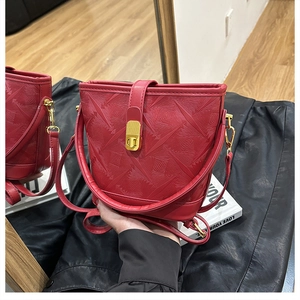 Detailed macro view of the embossed geometric texture and gold buckle on a red bucket bag