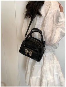 Detail of black quilted bag with silver mirror bow and double zipper closure