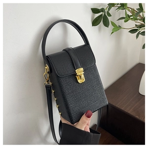 Detail of black denim phone bag with gold clasp and textured hard shell finish