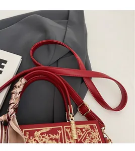 Detail of red wedding handbag featuring gold embroidery and a decorative silk scarf
