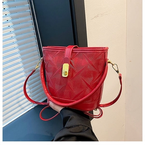 Detail of red bucket bag featuring geometric texture and gold metal buckle clasp