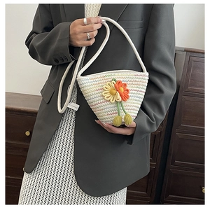 Close-up of handmade woven straw bucket bag with colorful floral embroidery details