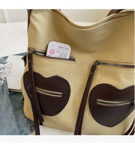 Detail view of beige canvas bag featuring dual brown heart-shaped zipper pockets and large space