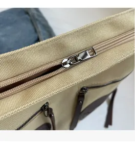 Detail view of smooth metal zipper and side pocket on a beige canvas tote bag