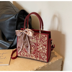 Detail of red wedding tote bag featuring gold embroidery and silk scarf handle accent