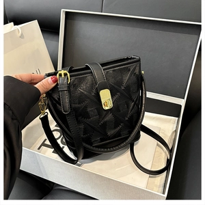 Detail of black textured bucket bag with geometric pattern and gold-tone metal hardware