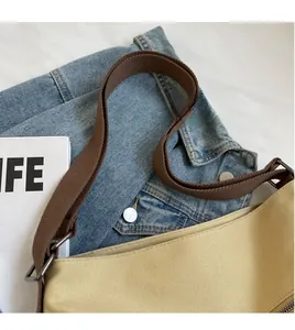 Detail of adjustable wide canvas shoulder strap on minimalist khaki tote bag with zipper