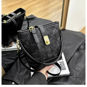 Detail of black bucket bag featuring radial geometric texture and gold metal hardware
