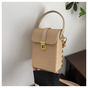 Detailed shot of beige textured leather phone bag with gold clasp and metal studs