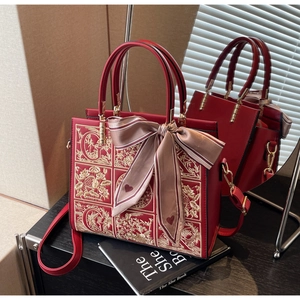 Detail of red wedding tote bag featuring gold floral embroidery and decorative silk scarf