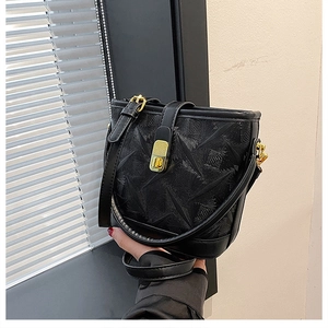 Detail of black bucket bag featuring geometric texture and gold metal clasp closure