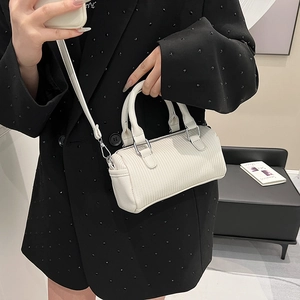 White mini Boston bag with vertical pleated texture and silver hardware held by a model