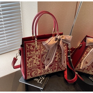 Detail of red bridal leather tote with gold floral embroidery and silk ribbon bow accent