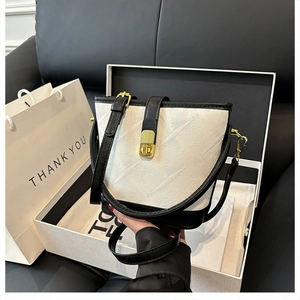 Close-up of contrast bucket bag with geometric texture in an elegant gift box setup