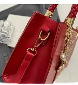 Close-up of red leather wedding bag with gold hardware, pearl pendant and floral pattern