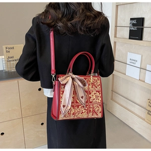 Detail of red bridal leather bag with golden K embroidery and heart print silk scarf
