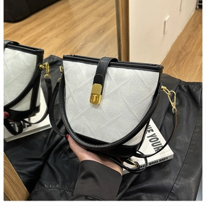 Detail of the white bucket bag featuring geometric embossing and a gold twist lock