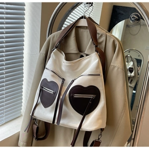 Close-up of canvas tote bag featuring unique brown heart-shaped zipper pockets and straps