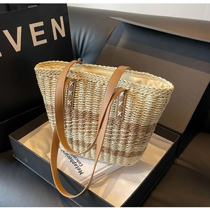 Detail of woven straw tote bag in beige and light coffee with brown leather handles