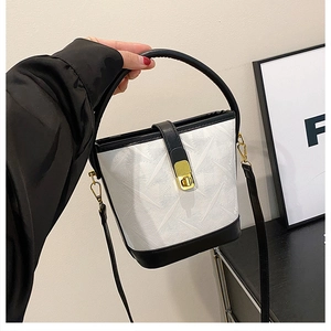 Detail of white embossed bucket bag with black leather trim and golden twist lock