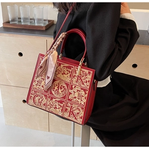 Detail of red wedding tote bag featuring golden floral embroidery and heart print silk scarf