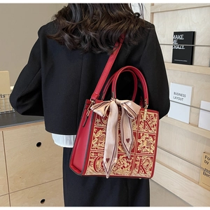 Detail of red bridal handbag with golden embroidery and elegant silk scarf accessory