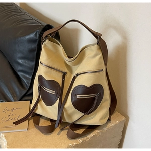 Detail of canvas tote bag featuring brown heart pockets and long fringe tassels