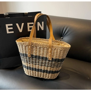 Macro detail of the woven straw texture and premium brown leather handle on a tote bag