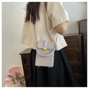 Detail view of light purple textured mini crossbody bag worn by a model in a cozy setting