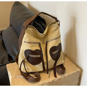 Detail view of canvas tote bag showing heart-shaped pockets and dark brown straps