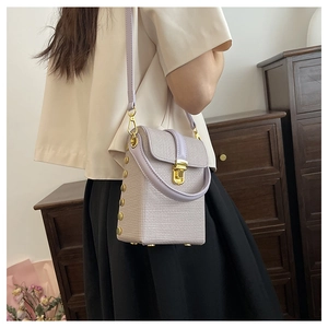 Detail view of light purple mini phone bag with golden studs and woven texture
