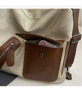Detail of canvas tote bag showing brown leather patch pocket and side zipper texture